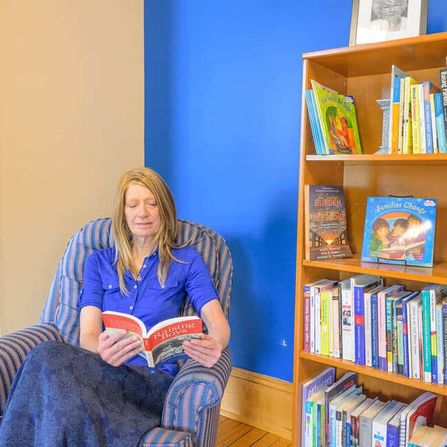 Tanya reading a book in Easterseals VT lending library.
