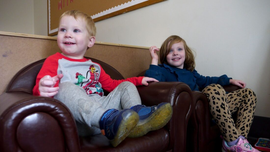 Zoey and theo sitting in brown leather chairs