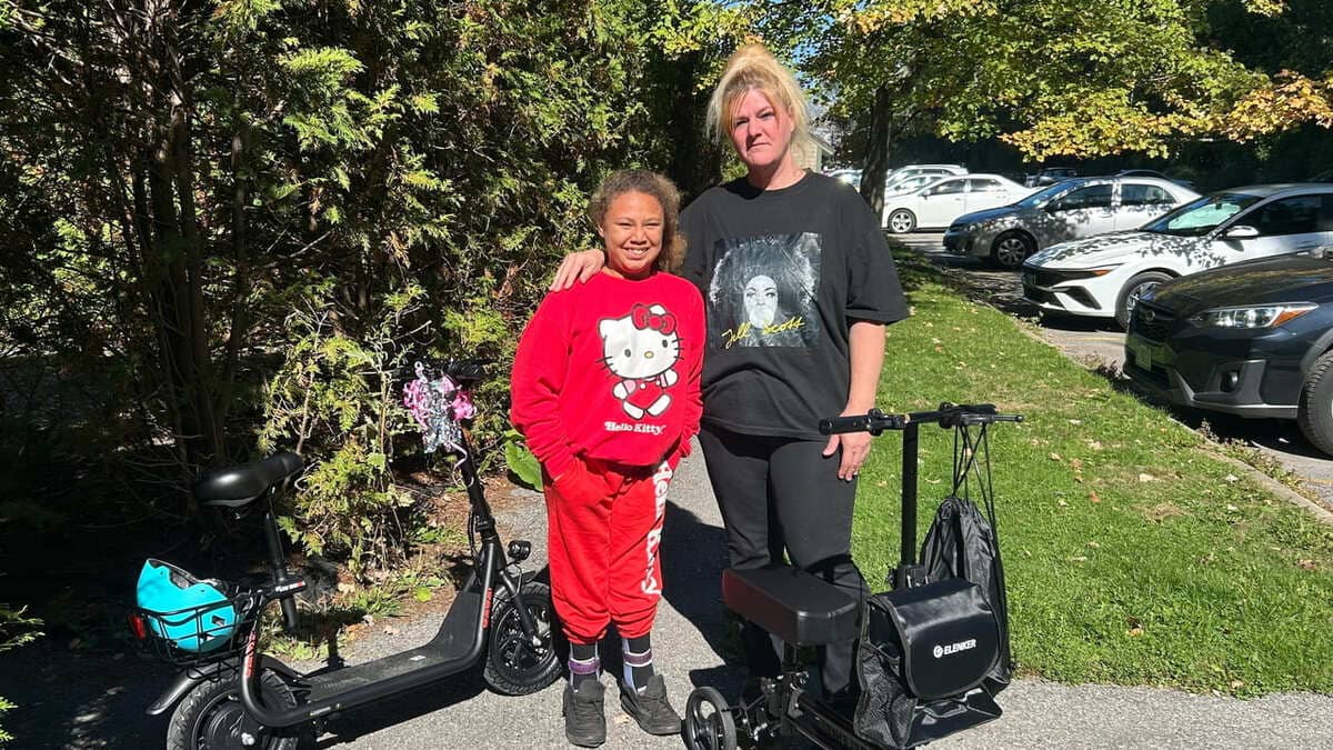 Destiny and her mother, Teri standing next to their electric scooters