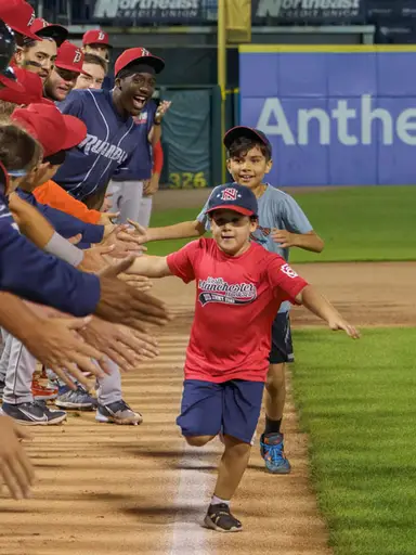 Two boys running down the baseline at a Fisher Cats baseball game.