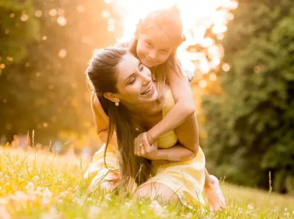 Mother and daughter playing in a grass field.